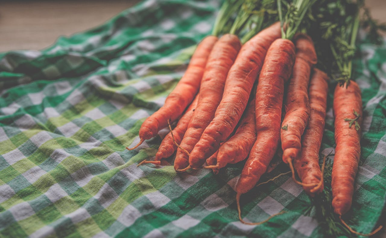 Bunch of fresh organic carrots displayed on vibrant checkered cloth.